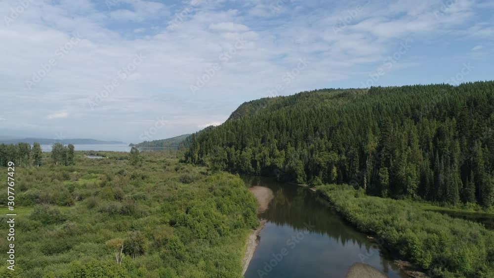 Drone, aerial, wide shot of a creek running through a forest area and leading out to a large river. Drone, aerial, wide shot of a creek running through a forest area and leading out to a large river.