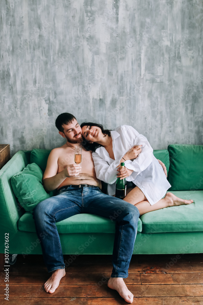 Obraz premium couple celebrating new year, green sofa, cozy at home