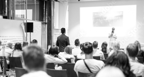 I have a question. Group of business people in conference hall. Businessman in audience standing and asking question to speeker. Conference and Presentation. Business and Entrepreneurship. photo