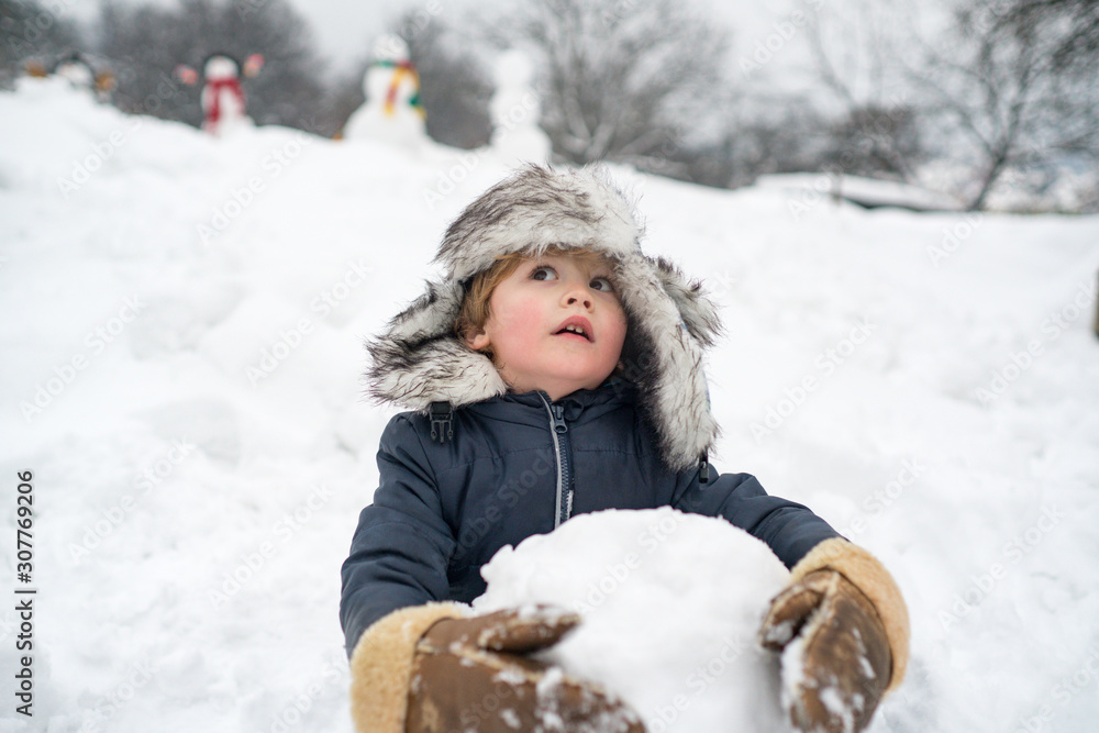 Fototapeta premium Funny boy posing on winter weather. Enjoying nature wintertime. Child playing with Snowman on snow background. People in snow. Snowman.