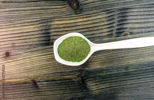 Coarse grind Mitragynina speciosa or Kratom powder in white ceramic spoon photo