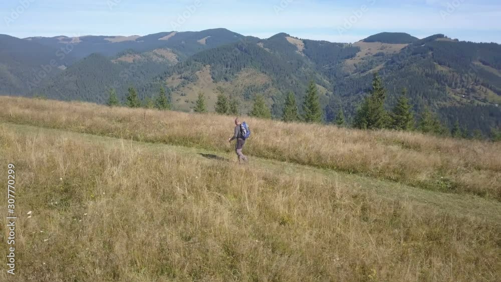 4K .Aerial. Life in travel. Man backpacker with sticks go on ridge in mountain hill. Fly around 4K .Aerial. Life in travel. Man backpacker with sticks go on ridge in mountain hill. Fly around
