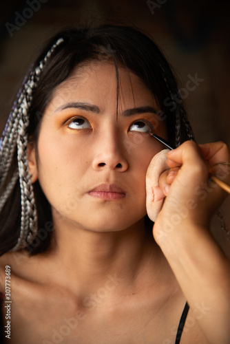 Makeup artist writing eyes for an Asian woman.
