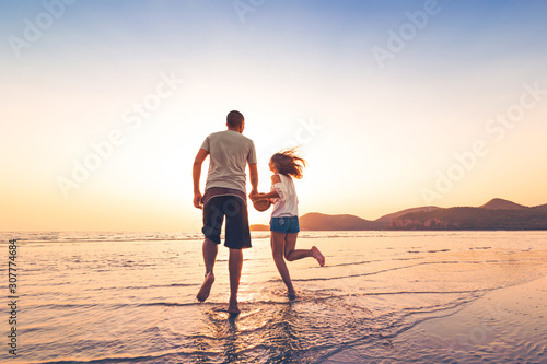 couple running and hand hold on the beach between sunset.