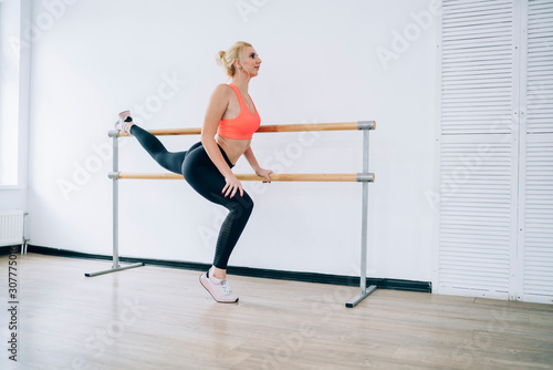 Young female athlete doing splits using ballet barre