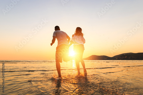 couple running and hand hold on the beach between sunset.