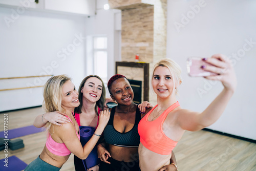 Multiethnic beautiful smiling women in sportswear taking selfie