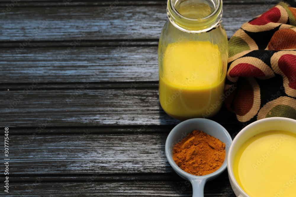 Turmeric latte, golden milk or the anti-inflammatory Indian Haldi Doodh with superfood Turmeric powder, Ginder and Cinnamon sweetened with honey on wooden background Turmeric latte, golden milk or the anti-inflammatory Indian Haldi Doodh with superfood Turmeric powder, Ginder and Cinnamon sweetened with honey on wooden background