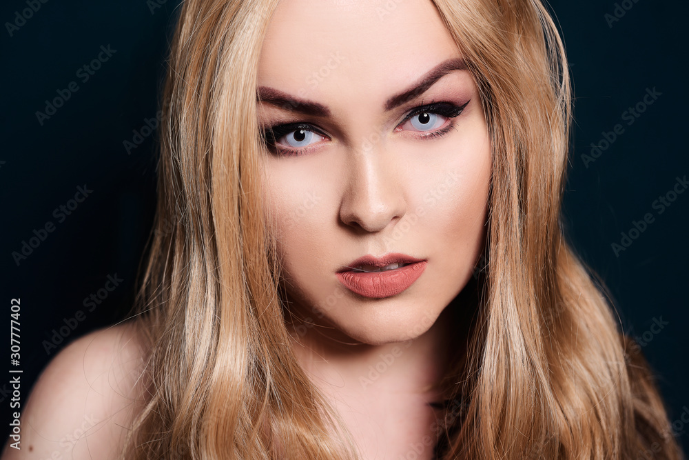 Blonde with long hair looking at the camera. Professional makeup, beautiful eyebrows, white lenses. Looking vampires, bright eyes. Hair care. Blindinka on a black back Blonde with long hair looking at the camera. Professional makeup, beautiful eyebrows, white lenses. Looking vampires, bright eyes. Hair care. Blindinka on a black back
