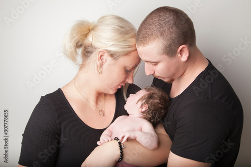 New family, mother and father holding new baby on white background