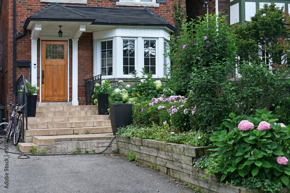 front yard of older brick detached house with hydrangea flowers in bloom