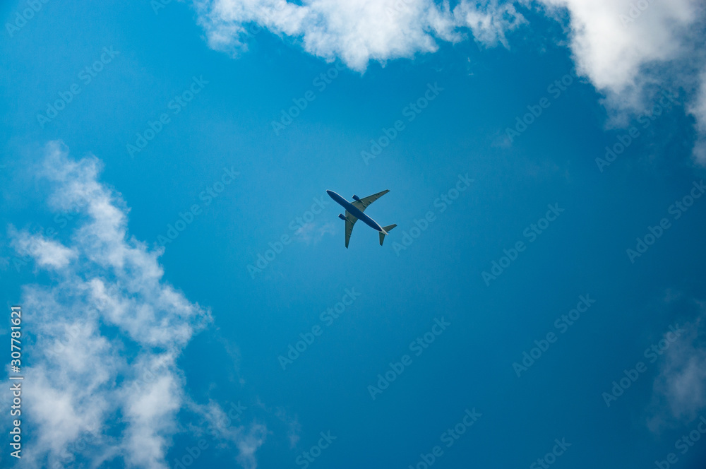 Passenger plane flies in blue sky with white clouds around