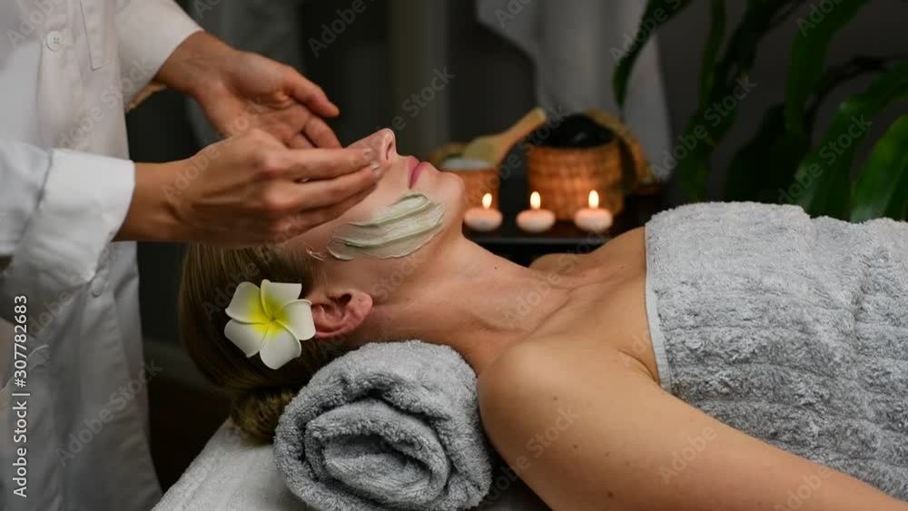 Cosmetologist is applying clay mask on female face, woman receiving beauty treatments in spa. Cosmetologist is applying clay mask on female face, woman receiving beauty treatments in spa.