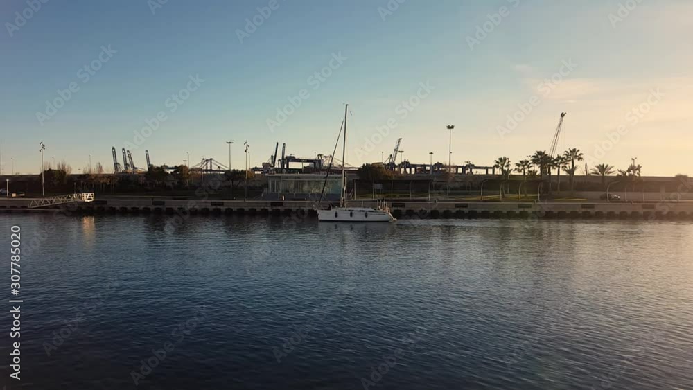 sailing yacht enters the port at sunset. port of Valencia Spain