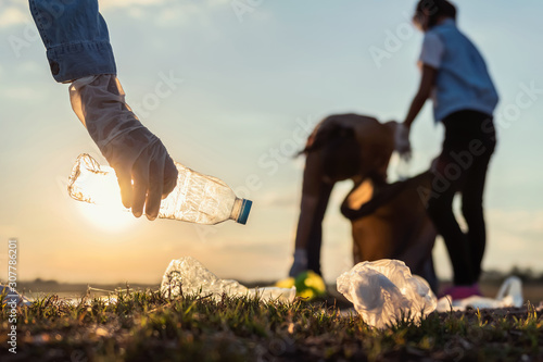 people volunteer keeping garbage plastic bottle into black bag at park river in sunset photo