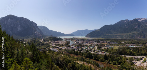 Aerial Panoramic view of residential homes in a small town with Chief Mountain in the background during a sunny summer day. Taken in Squamish, North of Vancouver, British Columbia, Canada.