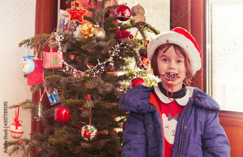 Child with cookie infront of Christmas tree Fototapet