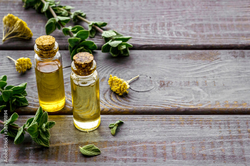 Aromatherapy. Essential oils in small bottles near fresh herbs on dark wooden background copy space