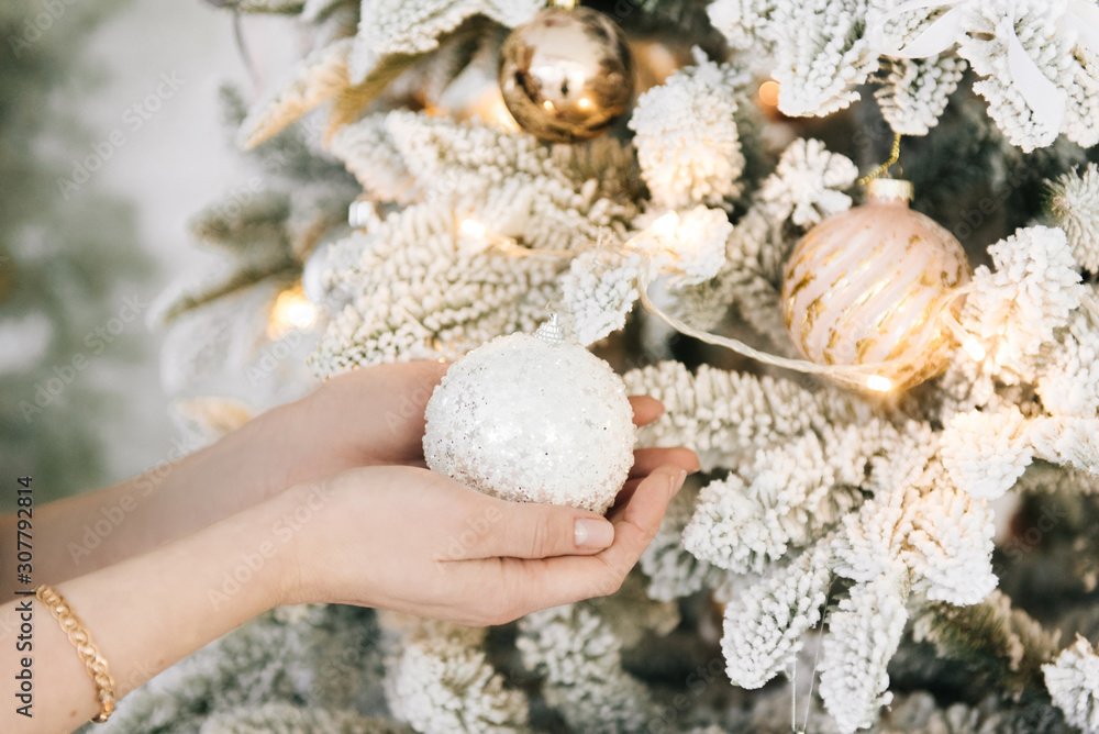 The girl's hands decorate the Christmas tree for the holiday, dress up with balls and garland The girl's hands decorate the Christmas tree for the holiday, dress up with balls and garland