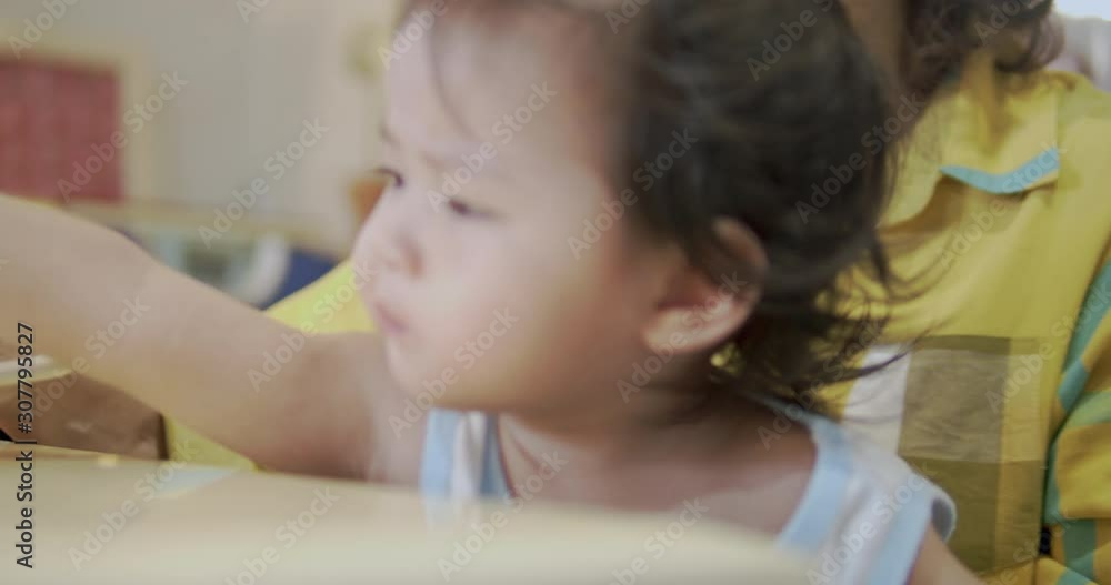 Grandmother using spoon feeding fresh food to her daughter.Asian baby girl open her mouth and eating food in the dining table at home. Grandmother using spoon feeding fresh food to her daughter.Asian baby girl open her mouth and eating food in the dining table at home.