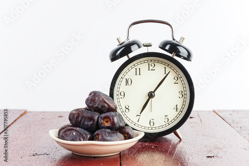 Dried dates fruit with the old clock over wooden table. Selective focus.