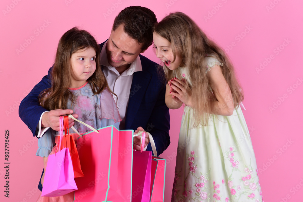 Schoolgirls and father hold pink packets looking inside
