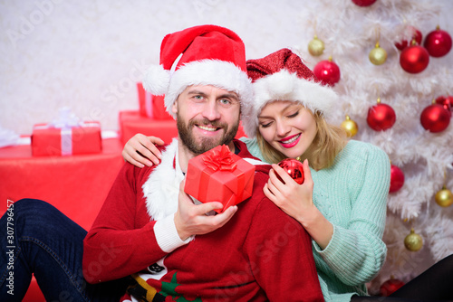 Loving couple cuddle smiling while unpacking gifts with christmas tree background. Family prepared christmas gifts. Christmas is time for giving. Couple in love enjoy christmas holiday celebration