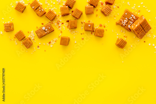 Salted caramel pieces - paradoxical sweets - on yellow background top view frame copy space photo