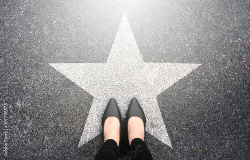 Success in business design concept. Businesswoman standing on street road background. Top view. Selfie of feet in black high heels shoes and white star symbol on pathway floor. New talent or champion. photo