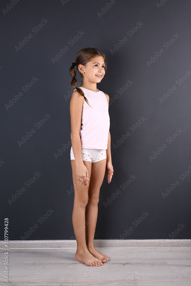 Cute little girl in underwear near dark wall Photos | Adobe Stock