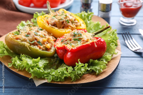 Tasty stuffed bell peppers served on blue wooden table, closeup