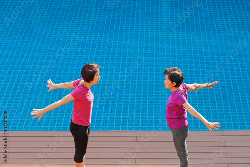 elderly woman doing exercise with daughter at pool patio © toa555