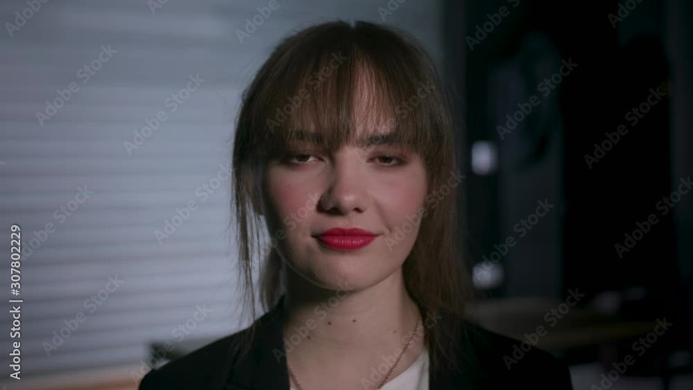 Young attractive woman looking into the camera, smiling with confidence. Dark garage environment. Young attractive woman looking into the camera, smiling with confidence. Dark garage environment.