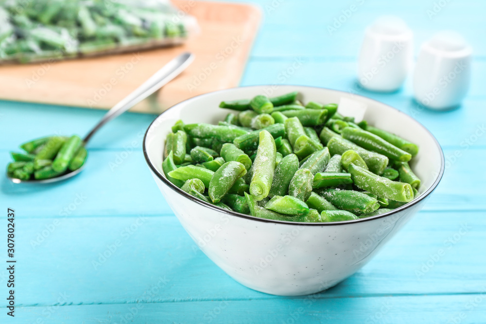 Frozen cut green beans on light blue wooden table, closeup. Vegetable preservation Frozen cut green beans on light blue wooden table, closeup. Vegetable preservation