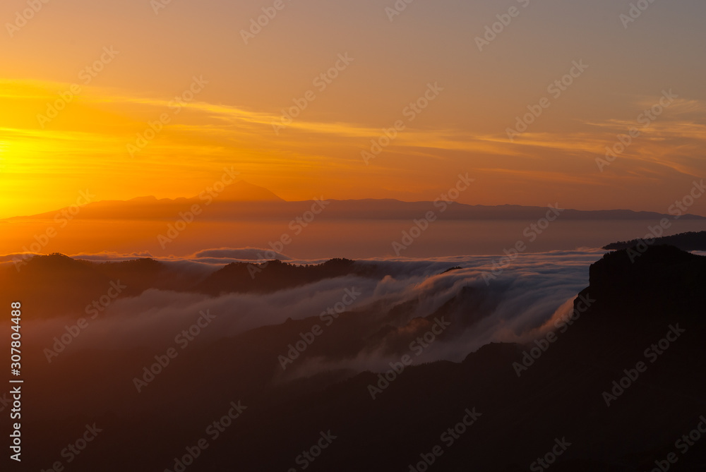 Sceninc overview over Gran Canaria facing Tenerife with the Teide from the mountain peak Pico de las Nieves during sunset