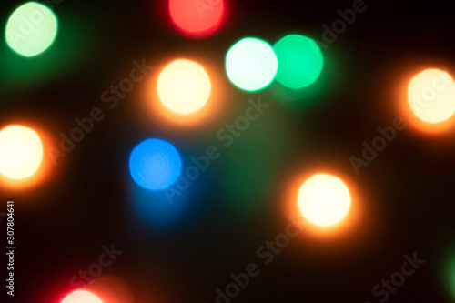 Multicolored blurry abstract lights with bokeh effect against a dark background. New Year's Christmas mood