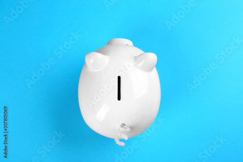 White piggy bank on blue background, top view