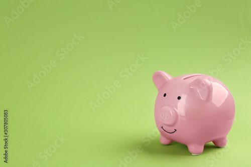 Pink piggy bank on green background. Space for text
