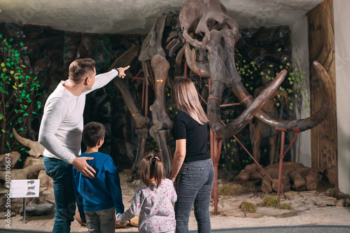 Family in the Museum. A family stands in front of a mammoth skeleton in the Museum of paleontology.