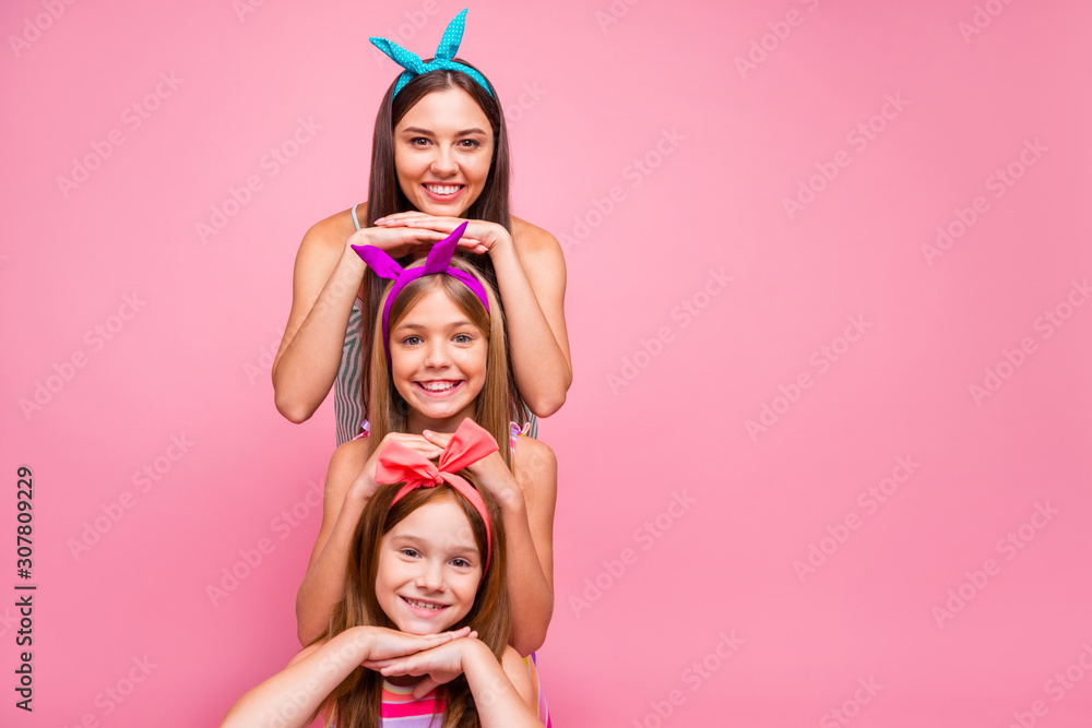 Close up photo of cute lades with headbands standing in stack isolated over pink background Close up photo of cute lades with headbands standing in stack isolated over pink background