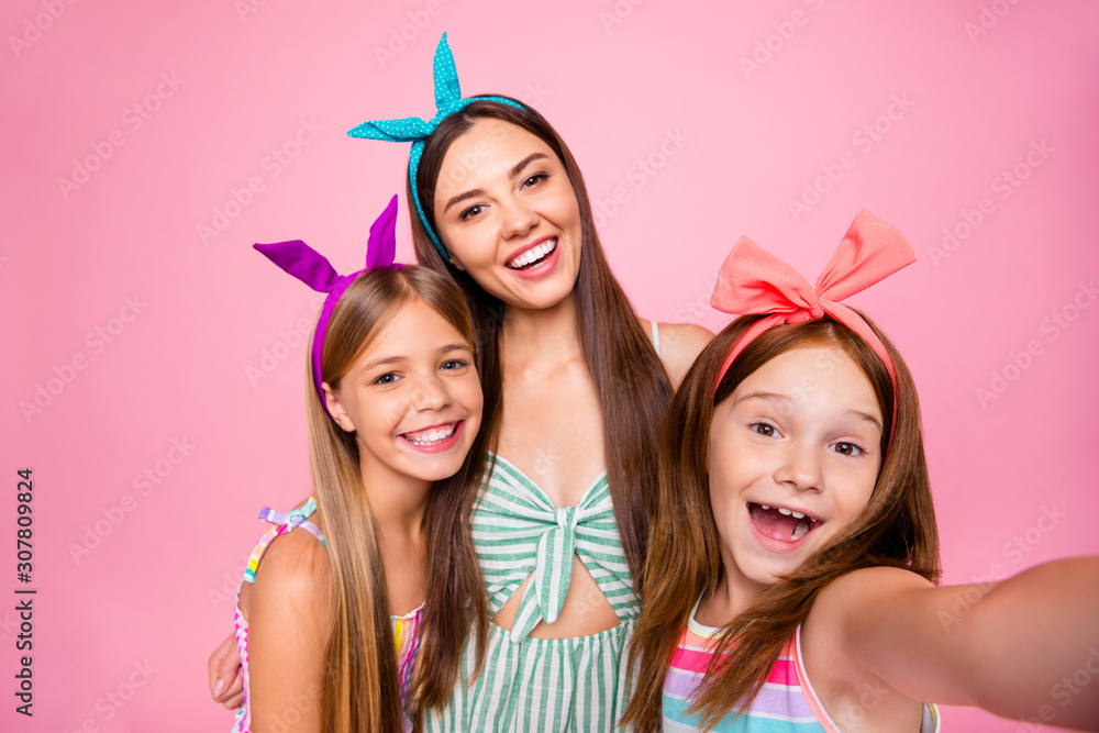 Close up photo of excited girls making self portrait wearing bright dresses isolated over pink background Close up photo of excited girls making self portrait wearing bright dresses isolated over pink background