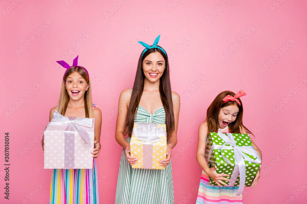 Portrait of cheerful siblings with headbands on long hairdo get giftbox for 8-march wearing skirt dress isolated over pink background Portrait of cheerful siblings with headbands on long hairdo get giftbox for 8-march wearing skirt dress isolated over pink background