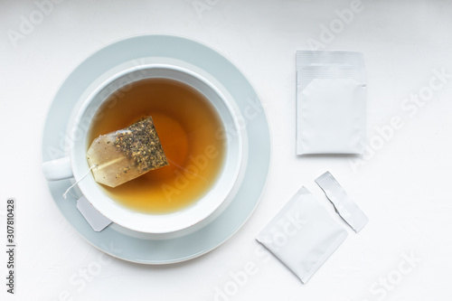 Cup with tea and mockup tag. Teabag pack copyspace mockup advertising design. Tea pack on white background. White tea sachet mock up.