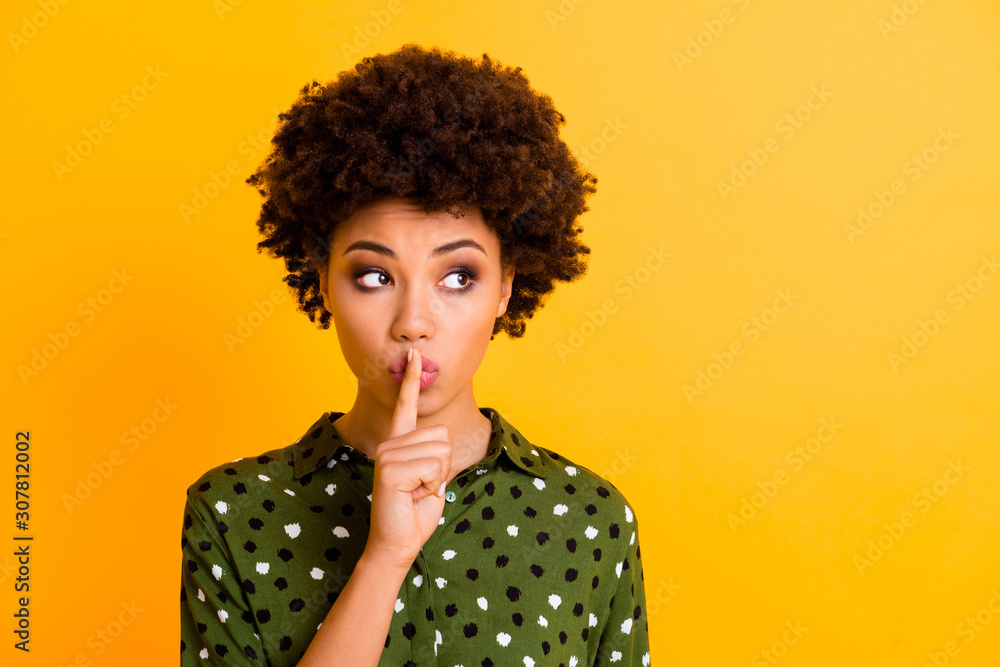 Photo of pretty dark skin wavy lady holding finger on lips asking keep silence looking wondered empty space wear trendy green dotted shirt blouse isolated yellow color background Photo of pretty dark skin wavy lady holding finger on lips asking keep silence looking wondered empty space wear trendy green dotted shirt blouse isolated yellow color background