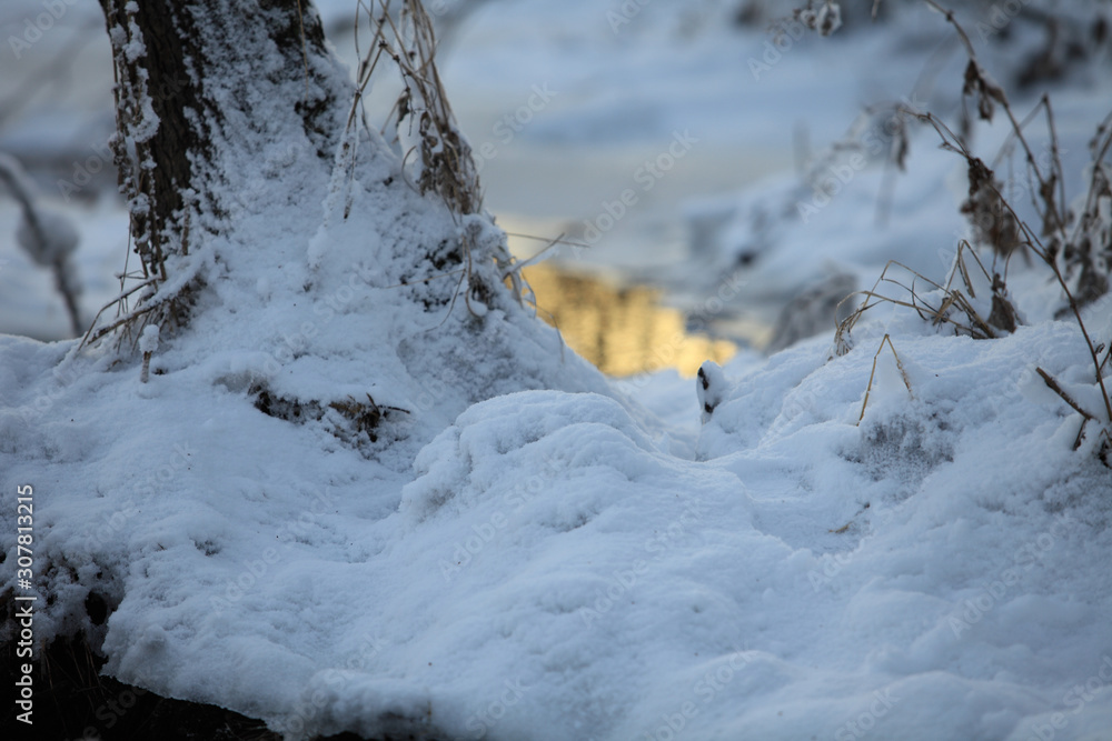 Winter snow and blurred stream reflects the setting sun behind Winter snow and blurred stream reflects the setting sun behind