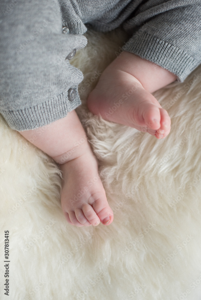A beautiful soft delicate warm young baby foot photographed with a shallow depth of field. gentle calm colours and feel. baby care and well being. babies feet on a cream fur rug. A beautiful soft delicate warm young baby foot photographed with a shallow depth of field. gentle calm colours and feel. baby care and well being. babies feet on a cream fur rug.