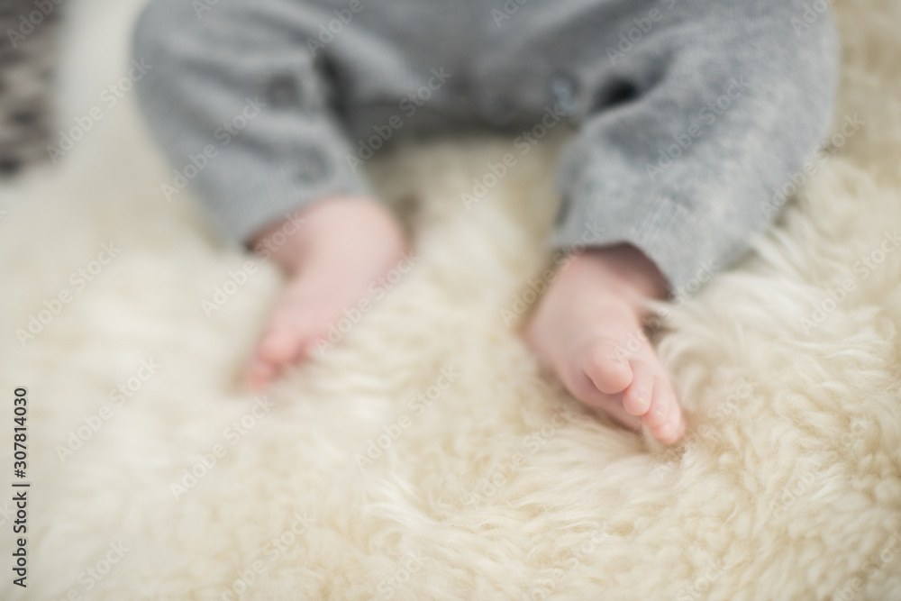 A beautiful soft delicate warm young baby foot photographed with a shallow depth of field. gentle calm colours and feel. baby care and well being. babies feet on a cream fur rug. A beautiful soft delicate warm young baby foot photographed with a shallow depth of field. gentle calm colours and feel. baby care and well being. babies feet on a cream fur rug.
