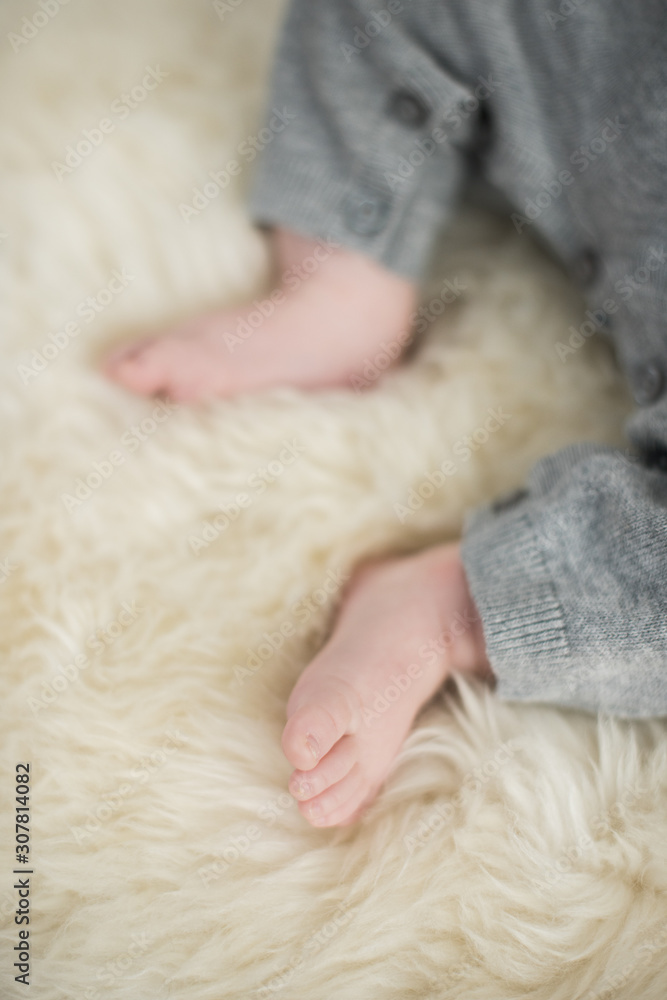 A beautiful soft delicate warm young baby foot photographed with a shallow depth of field. gentle calm colours and feel. baby care and well being. babies feet on a cream fur rug. A beautiful soft delicate warm young baby foot photographed with a shallow depth of field. gentle calm colours and feel. baby care and well being. babies feet on a cream fur rug.