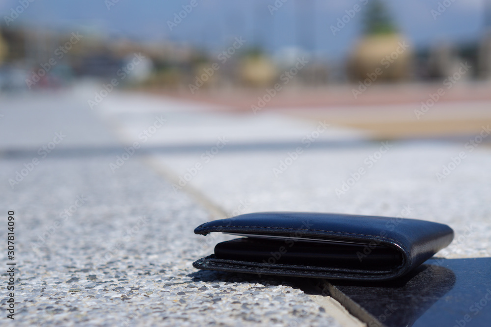 Closeup lost black leather wallet with money drop on the footpath, lost money concept Closeup lost black leather wallet with money drop on the footpath, lost money concept
