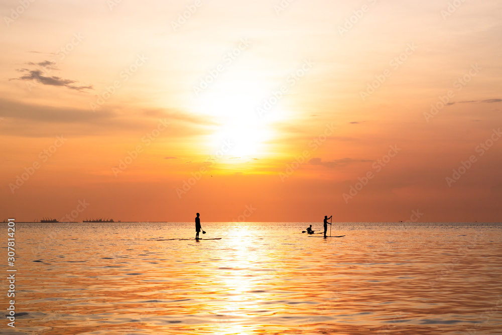 Silhouette of family playing the stand-up paddle board on the sea with beautiful summer sunset colors. Happy family concept. Silhouette of family playing the stand-up paddle board on the sea with beautiful summer sunset colors. Happy family concept.